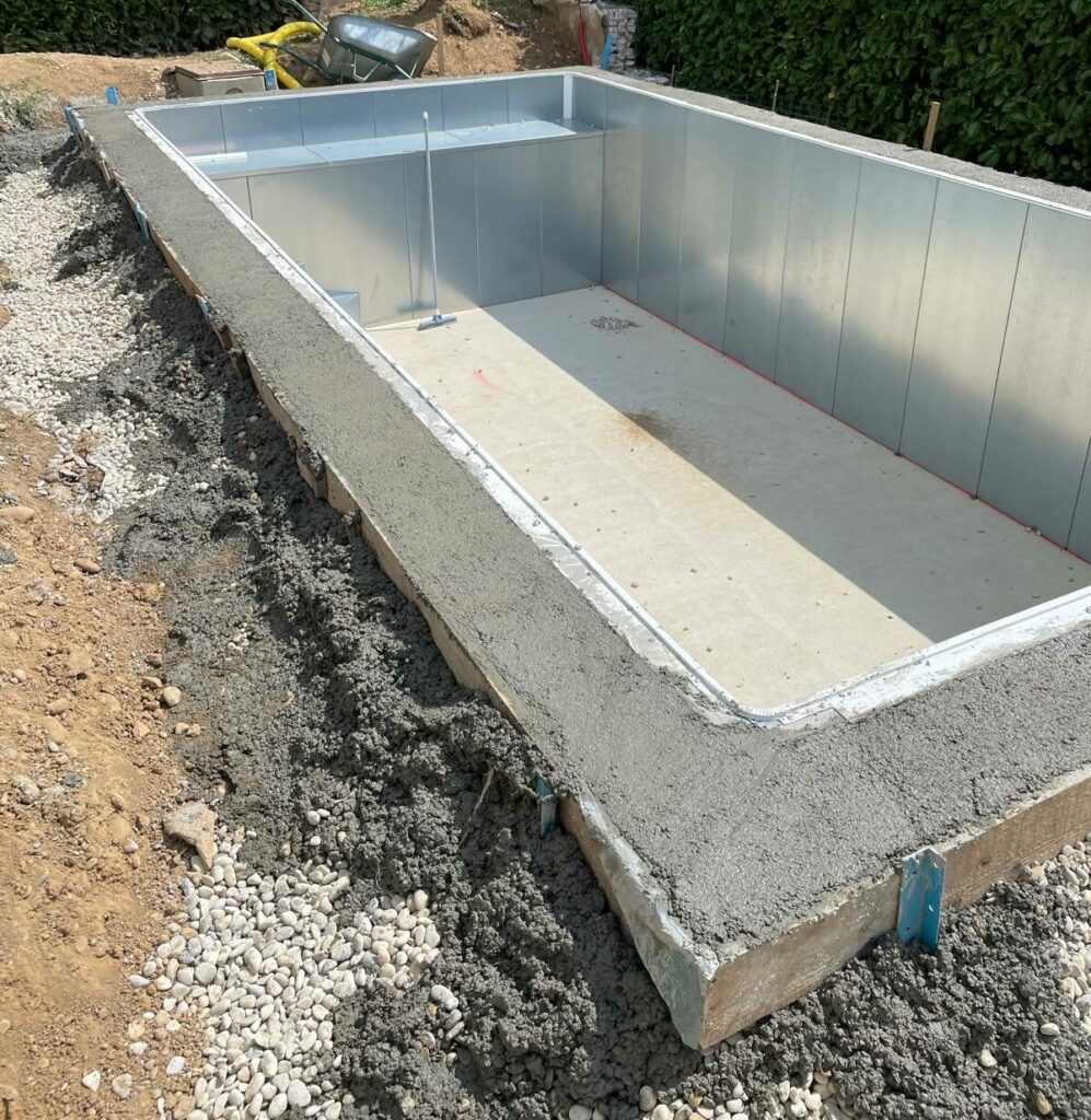 Piscine Aquinox en cours de construction avec panneaux en acier galvanisé et fond du bassin préparé avant revêtement 